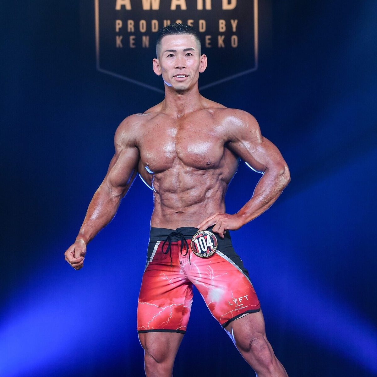 サーフパンツ姿で片手を腰に当て、フロントポーズをとるサマースタイルアワードのフィジーク選手