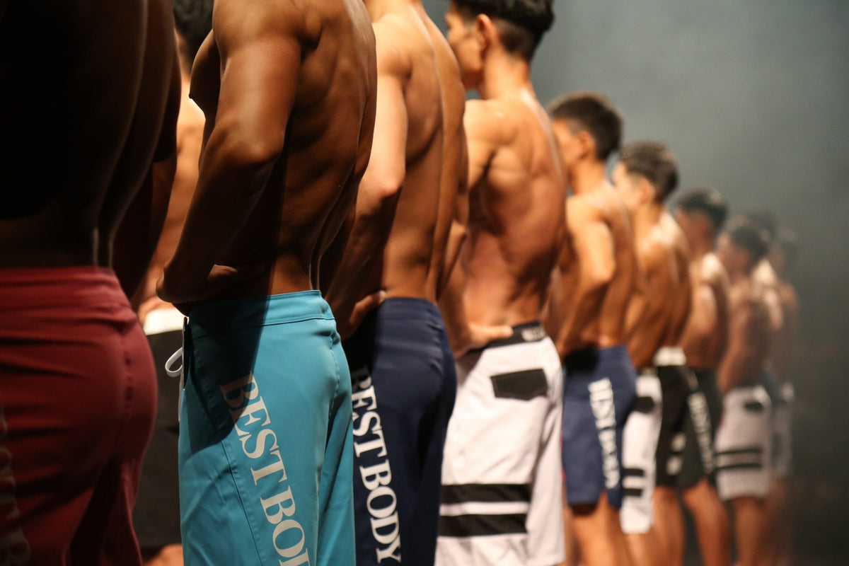 BEST BODYのロゴ入りサーフパンツでステージに並ぶ男性出場者たち