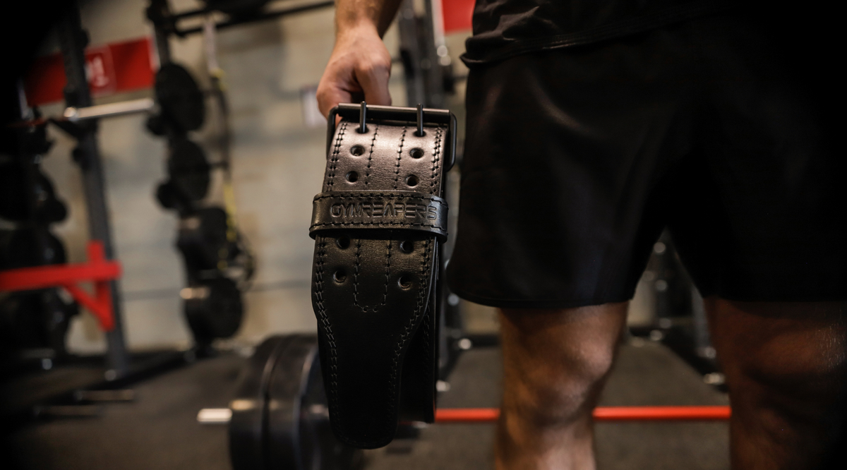 Gymreapersの黒い本革トレーニングベルトを手に持つ様子