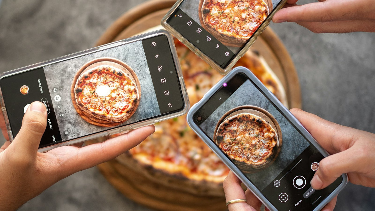 スマートフォンでピザの写真を撮る手元