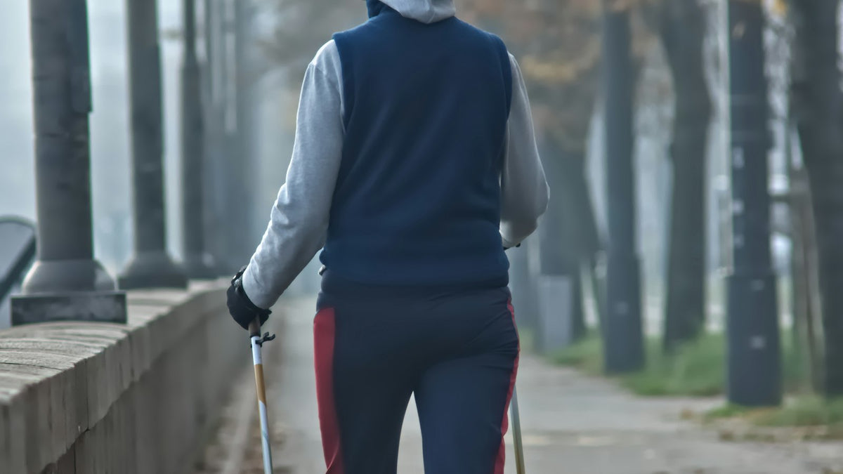 並木道をポールを使って歩く女性